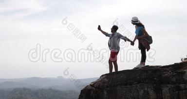 游客、情侣<strong>站在山顶</strong>在手机智能手机上制作视频景观，青年男女旅行者手持